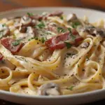 A delicious plate of Spaghetti Carbonara topped with crispy pancetta and grated cheese.