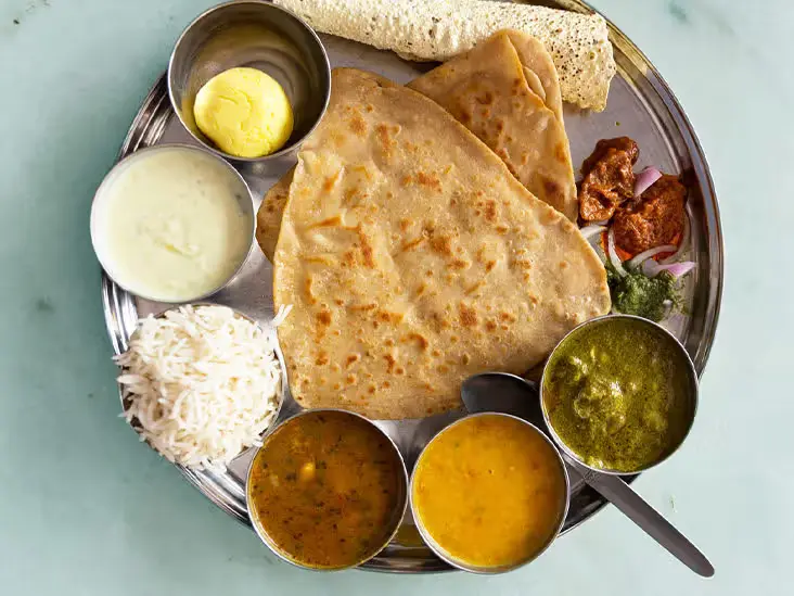 A vibrant North Indian thali showcasing butter chicken, naan, dal makhani, paneer tikka masala, and refreshing raita.