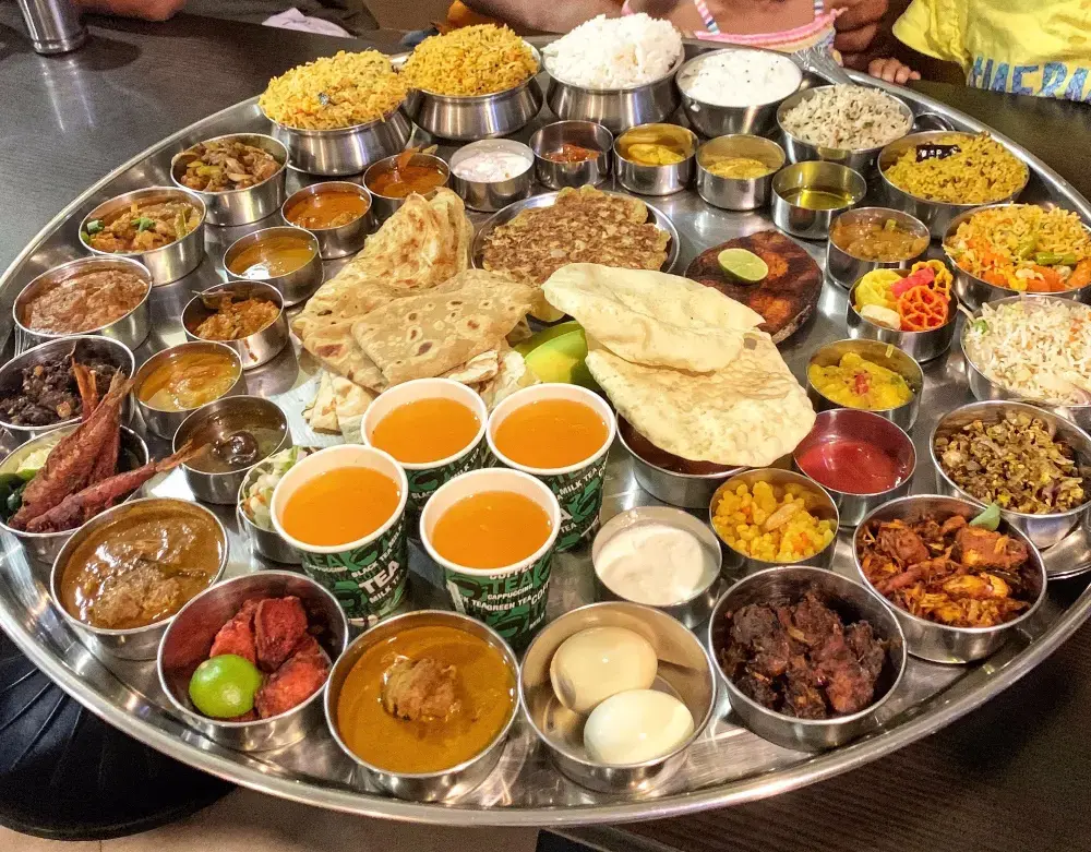 A traditional South Indian thali meal presented on a banana leaf with rice, sambar, rasam, and a variety of vegetable curries.
