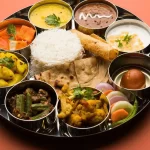 A rich and flavorful Bengali thali with steamed rice, fish curry, moong dal, shukto, and traditional sweets like sandesh and rasgulla.