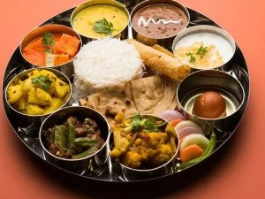 A rich and flavorful Bengali thali with steamed rice, fish curry, moong dal, shukto, and traditional sweets like sandesh and rasgulla.